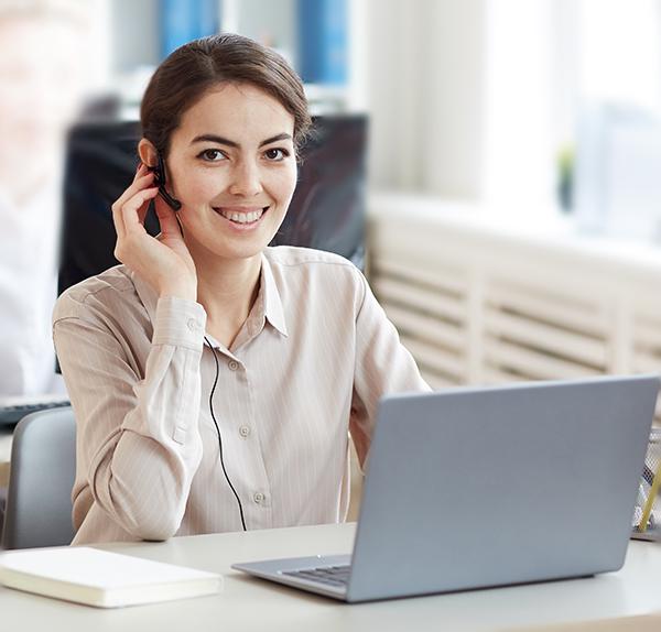 Contact us. Woman operator sitting at in row , focus on smiling woman looking at camera while talking to customer via headset